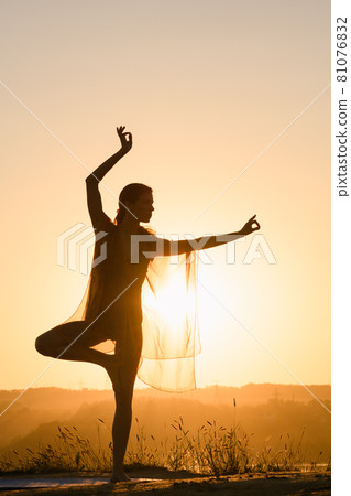Woman stand on one leg against sun Woman stand on one leg against sun 81076832