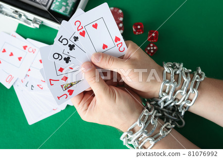 Men hands are tied with chain and hold playing cards closeup Men hands are tied with chain and hold playing cards closeup 81076992