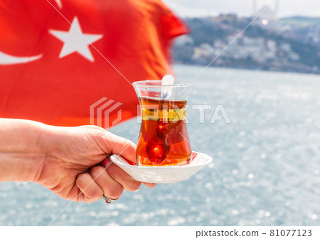 hand with turkish tea cup and flag. Travel concept hand with turkish tea cup and flag. Travel concept 81077123