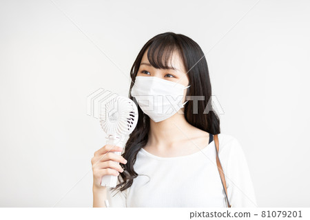 Young woman using a handy fan Young woman using a handy fan 81079201