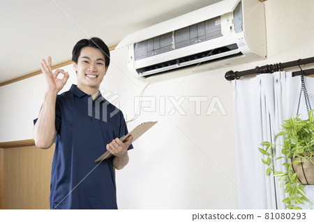 House cleaning worker giving an okay sign after cleaning the air conditioner 81080293