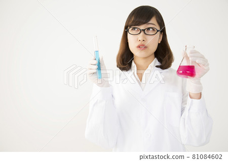 一個穿著實驗室外套的年輕女人，帶著一個燒瓶和一個斜著抬頭的考官 81084602