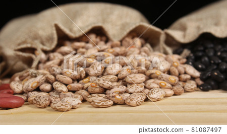 Burlap Bag of Dried Pinto Beans Spilled on Wooden Table Burlap Bag of Dried Pinto Beans Spilled on Wooden Table 81087497