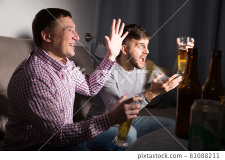 Exalted male friends watching tv at home Exalted male friends watching tv at home 81088211