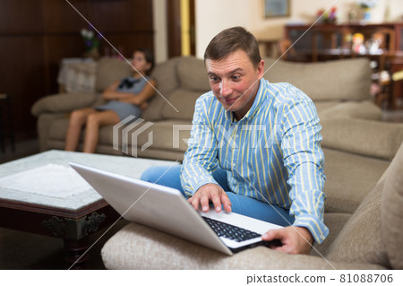 Man with laptop ignoring his disgruntled wife Man with laptop ignoring his disgruntled wife 81088706
