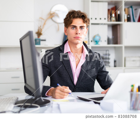 Focused attractive young man working with laptop and documents 81088708