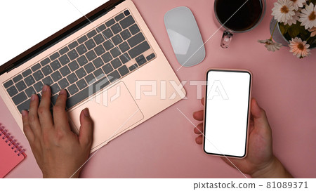 Woman holding mobile phone and using laptop computer. Woman holding mobile phone and using laptop computer. 81089371
