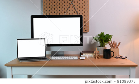 Front view modern workplace with computer, laptop and supplies on wooden table. Front view modern workplace with computer, laptop and supplies on wooden table. 81089373