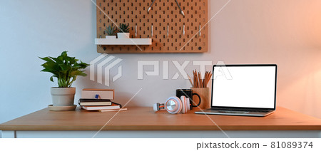 Computer laptop with lank screen, houseplant and supplies on wooden desk. 81089374