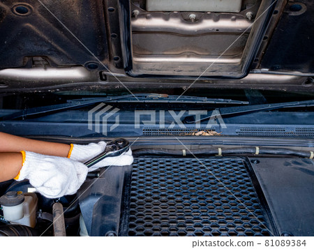 Mechanic holding a block wrench handle while fixing a car. Mechanic holding a block wrench handle while fixing a car. 81089384