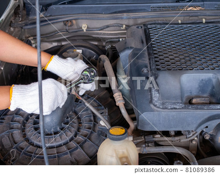 Mechanic holding a block wrench handle while fixing a car. Mechanic holding a block wrench handle while fixing a car. 81089386