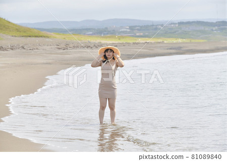 Taking a portrait of a woman in a mini one-piece in a straw hat on the coast of Esashi-cho, Hokkaido in midsummer 81089840