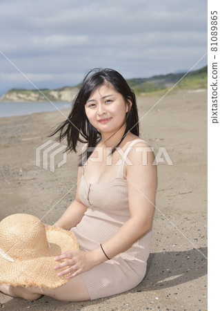 Taking a portrait of a woman in a mini one-piece in a straw hat on the coast of Esashi-cho, Hokkaido in midsummer 81089865