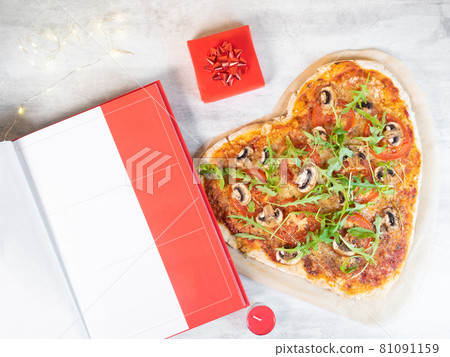 Heart shaped pizza with open book on the table 81091159