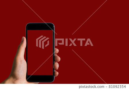 Female holding a black smartphone with a touch screen in Red background. 81092354
