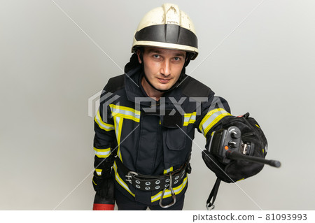 One male firefighter dressed in uniform posing over white studio background. One male firefighter dressed in uniform posing over white studio background. 81093993