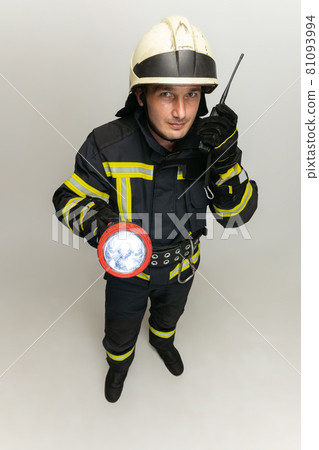 One male firefighter dressed in uniform posing over white studio background. One male firefighter dressed in uniform posing over white studio background. 81093994