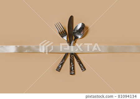 A set of cutlery - fork, spoon and knife. Top view. Pastel background A set of cutlery - fork, spoon and knife. Top view. Pastel background 81094134