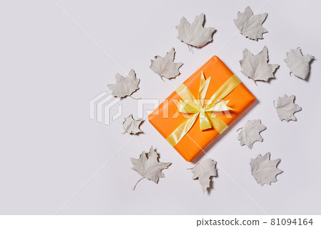 Gift boxes and fall leaves on white background. Creative lay out of autumn leaves and orange present boxes from above. Top view 81094164