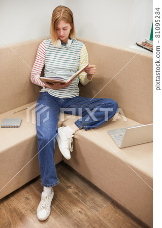 Young Woman Reading Book in College Young Woman Reading Book in College 81095284