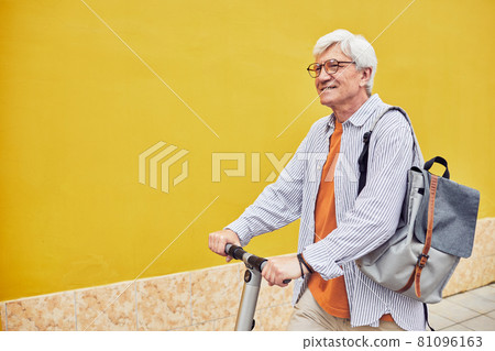 Active Mature Man Riding Scooter on Yellow Active Mature Man Riding Scooter on Yellow 81096163