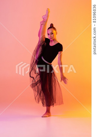 One young girl, rhythmic gymnastics artist in stage attire, skirt isolated on pink yellow studio background in neon. Concept of sport One young girl, rhythmic gymnastics artist in stage attire, skirt isolated on pink yellow studio background in neon. Concept of sport 81096836