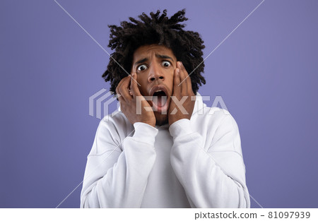 Black teen guy feeling scared, shouting in panic on violet studio background 81097939