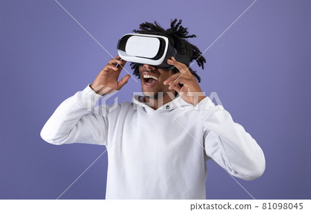 Funky Afro teen wearing VR headset, exploring cyberspace, using virtual reality for entertainment on violet background 81098045