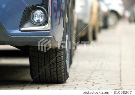 Closeup of parked car on a city street side with new winter rubber tires. Closeup of parked car on a city street side with new winter rubber tires. 81098267