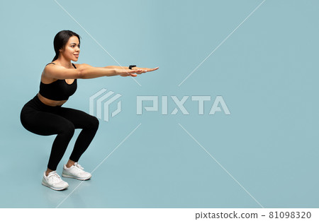 Fitness and sport. Slim african american lady doing deep squat exercises, working out over blue background, empty space Fitness and sport. Slim african american lady doing deep squat exercises, working out over blue background, empty space 81098320