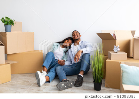 Real estate rent, mortgage and ownership concept. Happy black couple sitting among cardboard boxes, free space Real estate rent, mortgage and ownership concept. Happy black couple sitting among cardboard boxes, free space 81098385