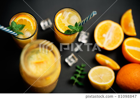 Delicious fresh orange juice with ice, mint and fresh fruits on black table background 81098847