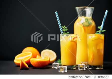 Delicious orange juice with ice, mint and fresh fruits on black table background with copy space 81098862