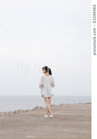 Back view of a woman standing on a breakwater (sideways) 81098968