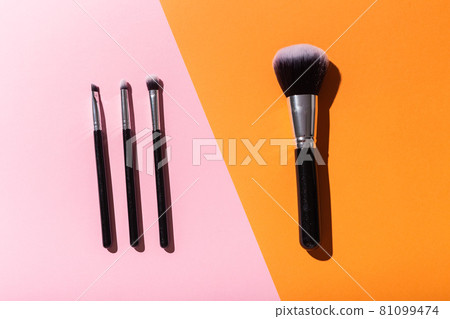 Various make-up brushes on pink and orange background, top view. Cosmetics and beauty concept. 81099474