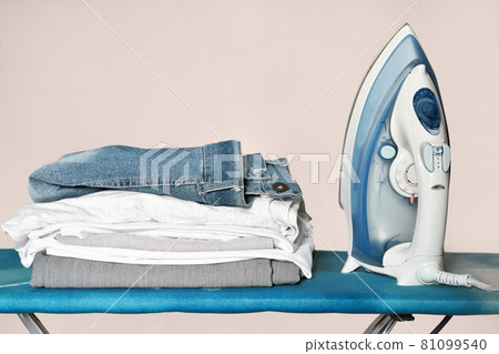 iron and a pile of clothes on the ironing board. chores and housekeeping routine, household work. iron and a pile of clothes on the ironing board. chores and housekeeping routine, household work. 81099540