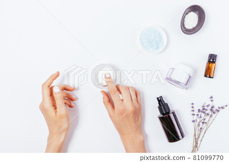 Female hands apply moisturizer next to lavender flowers 81099770