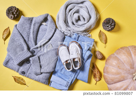 Baby autumn wear clothes on yellow background. Top view. Overhead view of warm kid autumn clothes on colored backdrop Baby autumn wear clothes on yellow background. Top view. Overhead view of warm kid autumn clothes on colored backdrop 81099807
