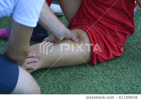 Male massagist hands massaging leg of the woman football player on the soccer field Male massagist hands massaging leg of the woman football player on the soccer field 81100656