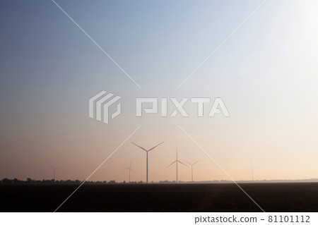 Windmills in the fog near a field of sunflowers. Early morning. See the movement of the blades, as a strong wind is blowing. Wind turbine are installed at different distances and hidden in the fog Windmills in the fog near a field of sunflowers. Early morning. See the movement of the blades, as a strong wind is blowing. Wind turbine are installed at different distances and hidden in the fog 81101112