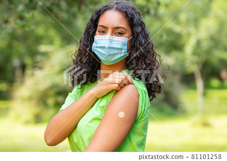 Vaccinated African American female young woman wearing face mask and vaccine band aid 81101258