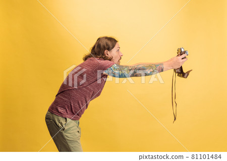 Portrait of young man, photographer, cameraman with retro camera isolated on yellow studio background. Concept of occupation, job, funny meme emotions 81101484