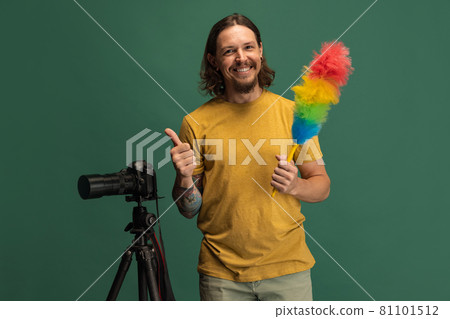 Comic portrait of young man, photographer, cameraman with retro camera having fun isolated on green studio background. Concept of occupation, job, funny meme emotions 81101512