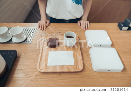 Female barista standing behind counter in coffee shop Female barista standing behind counter in coffee shop 81101614