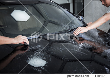 Mechanic installs car paint protection film. 81104650