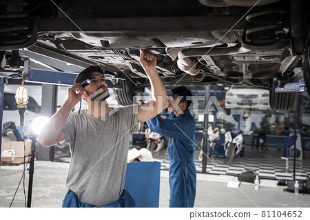 Two mechanic was checking the car suspension. 81104652