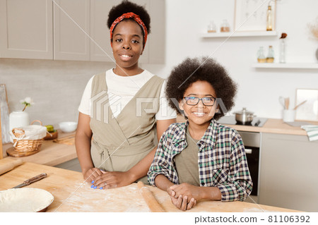 Happy mother and son standing by kitchen table 81106392