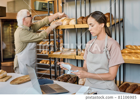 Serious young female checking receits in front of laptop by workplace 81106985