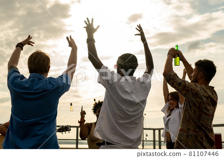 Joyful friends with beer raising arms while dancing 81107446