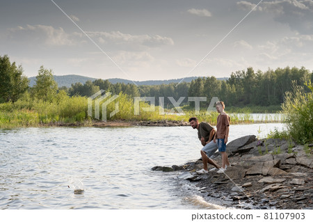Young man and teenage boy enjoying time by lake Young man and teenage boy enjoying time by lake 81107903